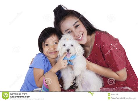 Cute Girl And Her Mother Holding Dog In Studio Stock Photo