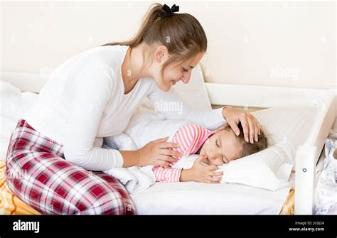 Young Brunette Mother Waking Up Sleeping Daughter At Morning Stock