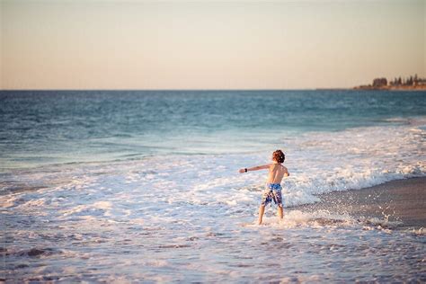 Child Riding A Skim Board At The Beach At Sunset By Stocksy