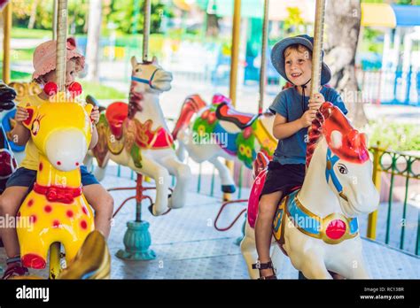 Cute Little Boy And Girl Enjoying In Funfair And Riding On Colorful