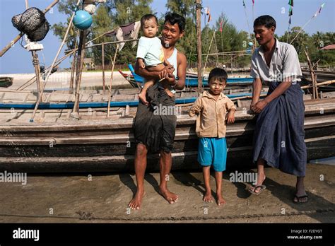 Two Local Men And Two Children Standing In Front Of Fishing Boats In