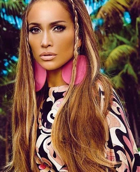 A Woman With Long Brown Hair And Pink Earrings Standing In Front Of