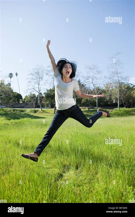 Hispanic Girl Jumping In A Grassy Field Stock Photo Alamy