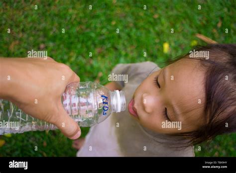 Little Children Drinking Water From Bottle In Green Park High