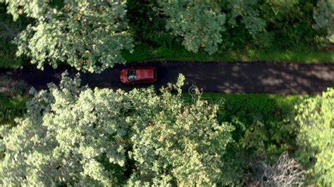Aerial View Of Red Car Driving On Country Road In Forest Stock Image