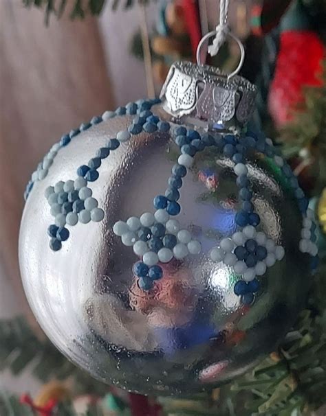 A Silver Ornament With Blue And White Beads On It Hanging From A