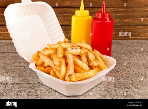 French Fries In Takeout Container Ketchup And Mustard Bottle On The