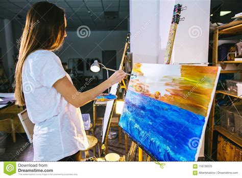 Woman Artist Painting A Picture On Easel With Oil Paints In Her