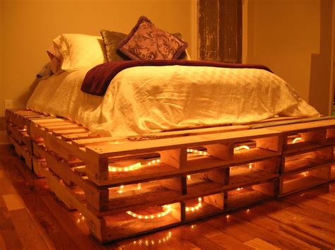 A Bed Made Out Of Wooden Pallets With Lights On Them