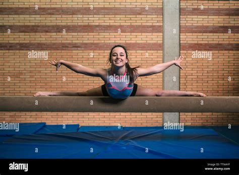 Full Length Portrait Of Female Gymnast With Legs Apart And Arms Outstretched Exercising On