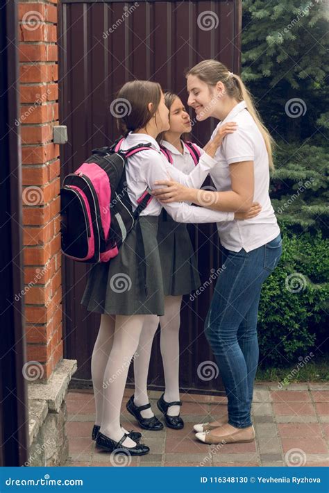 Toned Image Of Two Girls Kissing Mother Before Leaving To School Stock