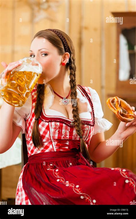 Young Woman In Traditional Bavarian Tracht In Restaurant Or Pub With Beer And Steins And Pretzel