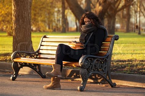 Young Sad Woman Sitting Alone On A Park Bench Stock