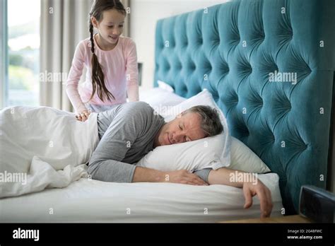 Girl Waking Her Sleeping Father Up In Bed Stock Photo Alamy