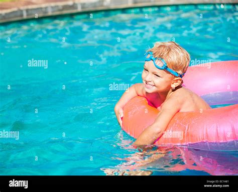 Young Kid Having Fun In The Swimming Pool On Inner Tube Raft Summer