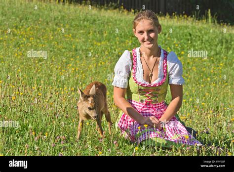 Frau Im Dirndl Mit Zahmen Faon In Einer Blumenwiese Tirol Österreich Stockfotografie Alamy