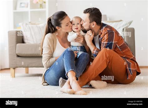 Happy Mother And Father Kissing Baby At Home Stock Photo Alamy