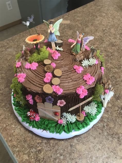 A Chocolate Cake Decorated With Flowers And Fairy Figurines Sitting On