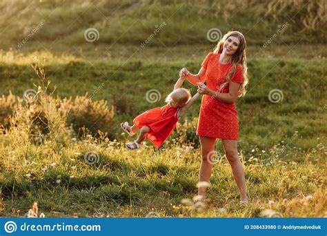 Portrait Of A Mother Holds Throws Up And Spins The Daughter On Hands