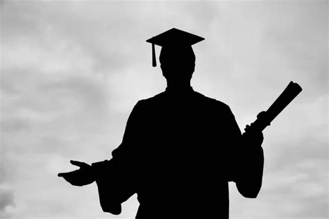 Silhouette Of Graduated Student Man In Cap Gown Showing Diploma Scroll