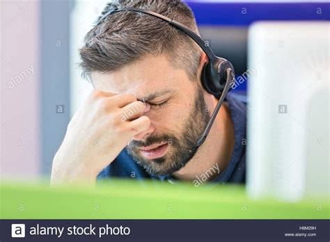 Tired Mid Adult Businessman Wearing Headset While Pinching Bridge Of