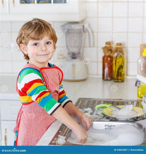 Happy Little Blond Kid Boy Washing Dishes In Domestic Kitchen Stock
