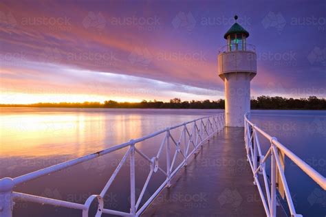 Image Of A Jetty Leading Out To A Lighthouse Under A Colourful Sunset