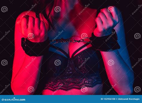 submissive girl`s hands in leather handcuffs for bdsm sex with submission next to her breasts in