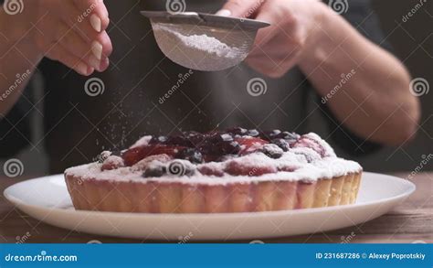 Woman Sprinkling A Cake With Powdered Sugar Through Metal Sieve Stock