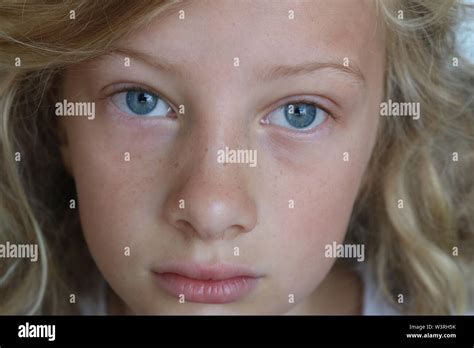 Closeup Of A Beautiful Preteen Girl With Blue Eyes And A Sad Serious