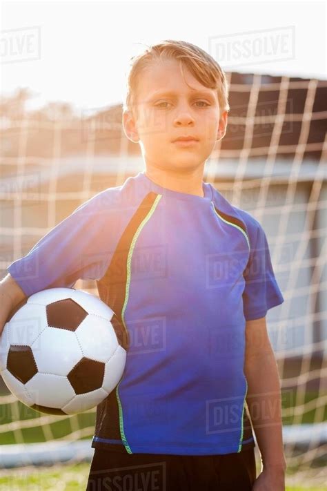 Portrait Of Boy Football Player Holding Football In Front Of Goal