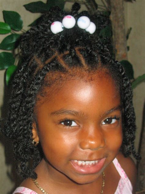 Cuddly and cute kid, with two small ponytails secured in a side parted manner with a beautiful clip tucked on front to enhance her charm. Black Kids Hairstyles | Beautiful Hairstyles