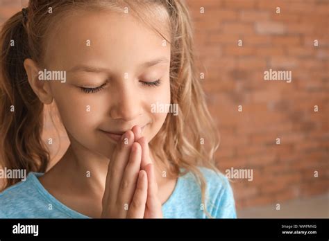 Cute Little Girl Praying Against Brick Wall Stock Photo Alamy