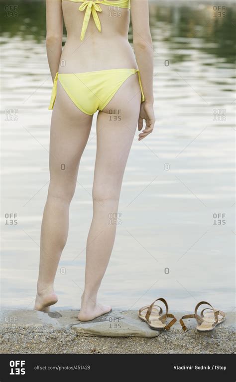 Rear View Of Woman Wearing Yellow Bikini Standing At Lakeshore Stock