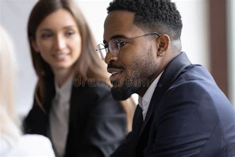 Confident Biracial Male Employee Talk At Meeting With Colleagues Stock
