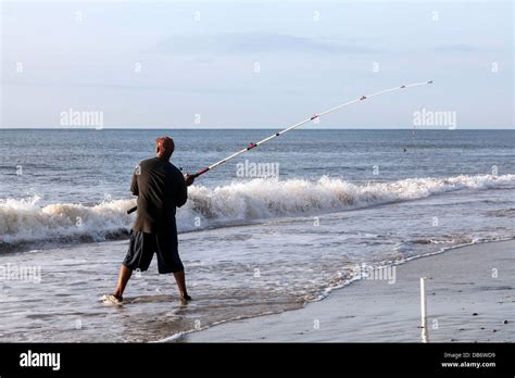 Sea Angler With Fishing Rod Pole On Beach Along The Coast Casting