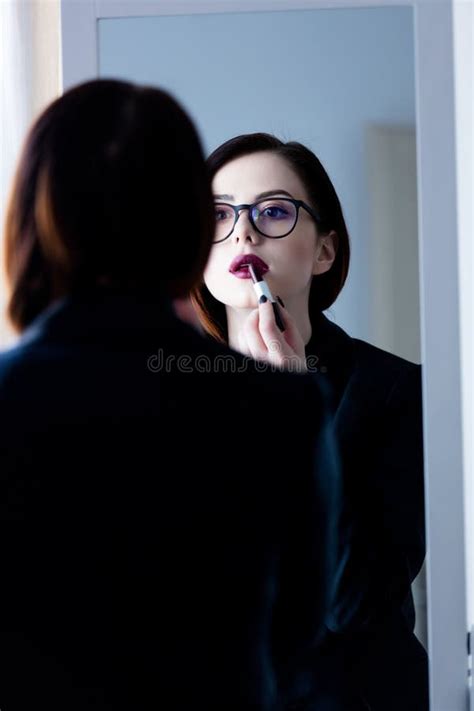 Beautiful Young Woman Standing In Front Of Mirror Putting On Li Stock