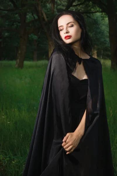 Beautiful Brunette Woman In Black Dress And Black Cloak In The M Stock