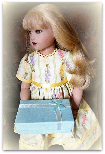 A Doll With Blonde Hair Holding A Blue T Box