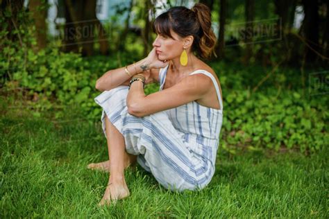 Mid Adult Woman Sitting Cross Legged In Garden Stock Photo Dissolve