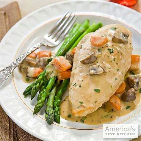 A White Plate Topped With Chicken Covered In Gravy And Asparagus