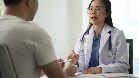 asian female doctor with male patient during consultation in health clinic doctor sitting stock