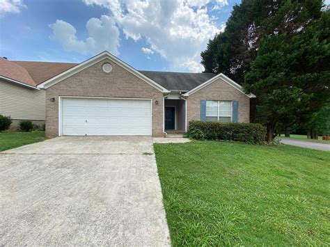 A House With A Driveway In Front Of It And Grass On The Lawn Next To It