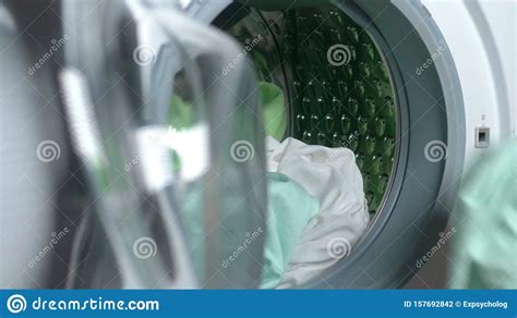 Close Up Female Hands Put Fabric In A Washing Machine Stock Photo
