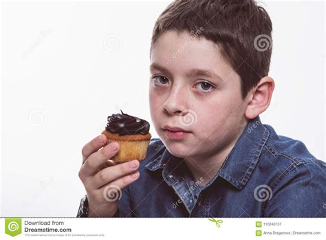Young Boy With Denim Shirt Eating Chocolate Cupcake On White Isolated