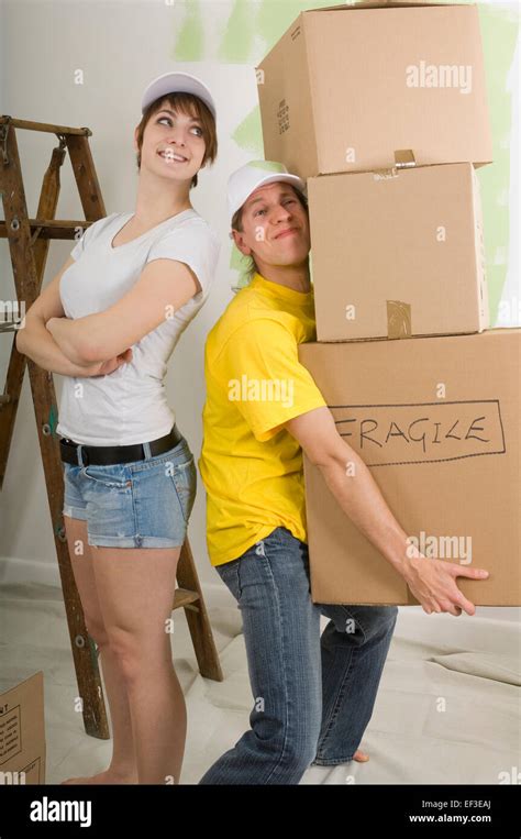 Man Carrying Heavy Boxes While Woman Watches Stock Photo Alamy
