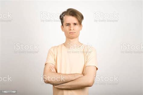 Portrait Of A Frustrated And Frowning Guy With Crossed Arms On A White