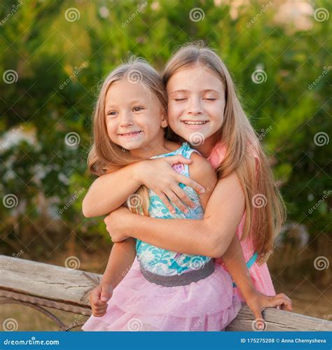 Two Little Girls Sisters Hugging And Having Fun In Park Stock Photo