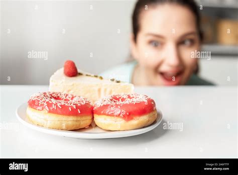 Body Care Chubby Girl Hiding Under Table In Kitchen Looking At Plate With Desserts Close Up