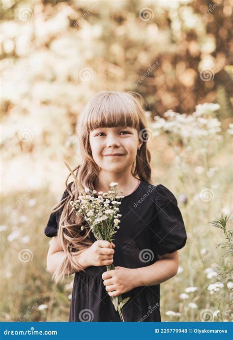 Little Girl In Black Stylish Dress In Nature In The Summer With Flowers